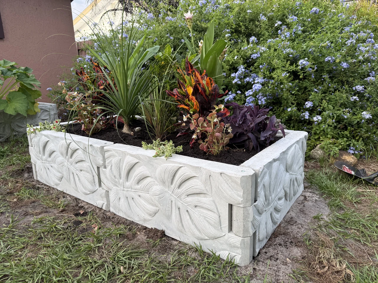 Corner view of a concrete raised bed filled with tropical plants