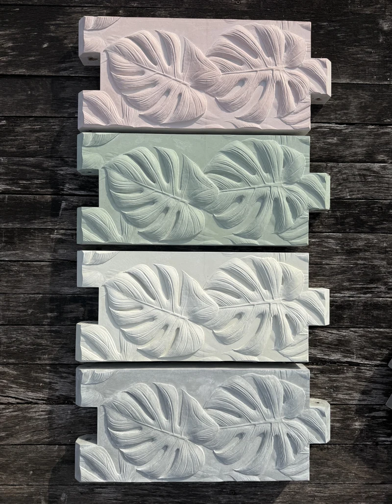 Several botanical-relief concrete panels stacked on a work surface