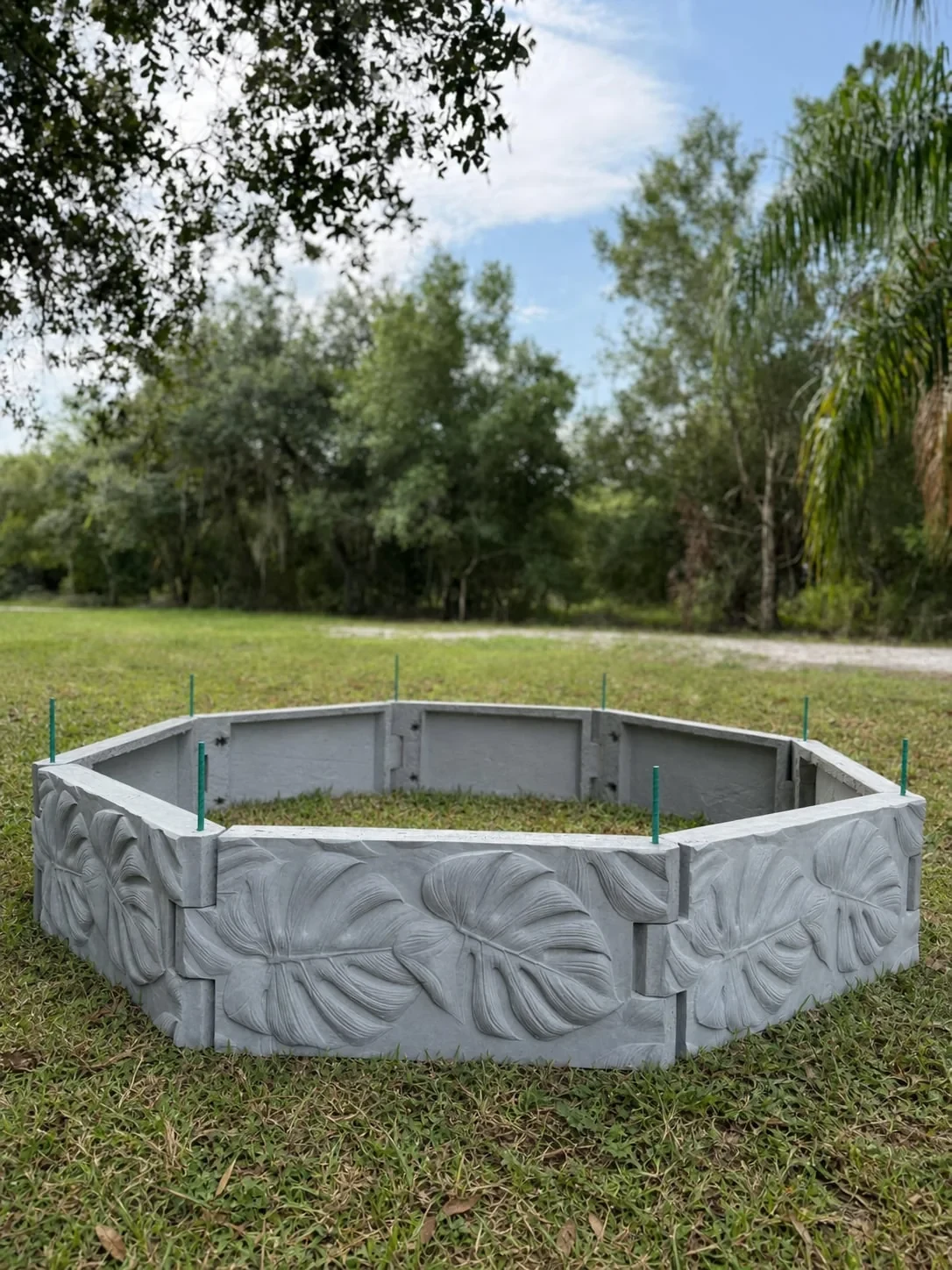 Front view of an empty octagonal Radical raised garden bed with sculpted leaf-pattern panels